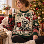 woman sitting in christmas sweater holding tree mug beside lit tree
