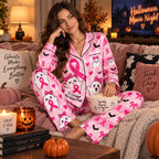woman sitting on bed wearing pink ghost print satin pyjamas with mug