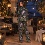 woman in a witchy halloween satin pajama set sitting on a bed