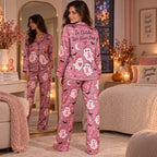 woman sitting on bed wearing pink satin halloween pyjamas with ghost and