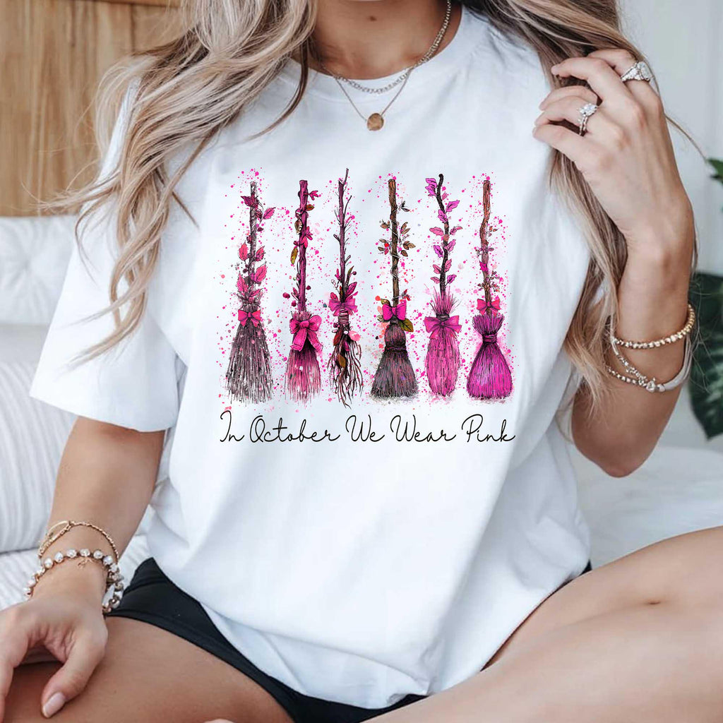 white graphic tee with pink witch broom design worn by a woman