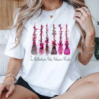 white graphic tee with pink witch broom design worn by a woman