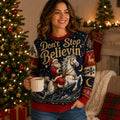 woman holding mug in front of lit christmas tree wearing ugly christmas