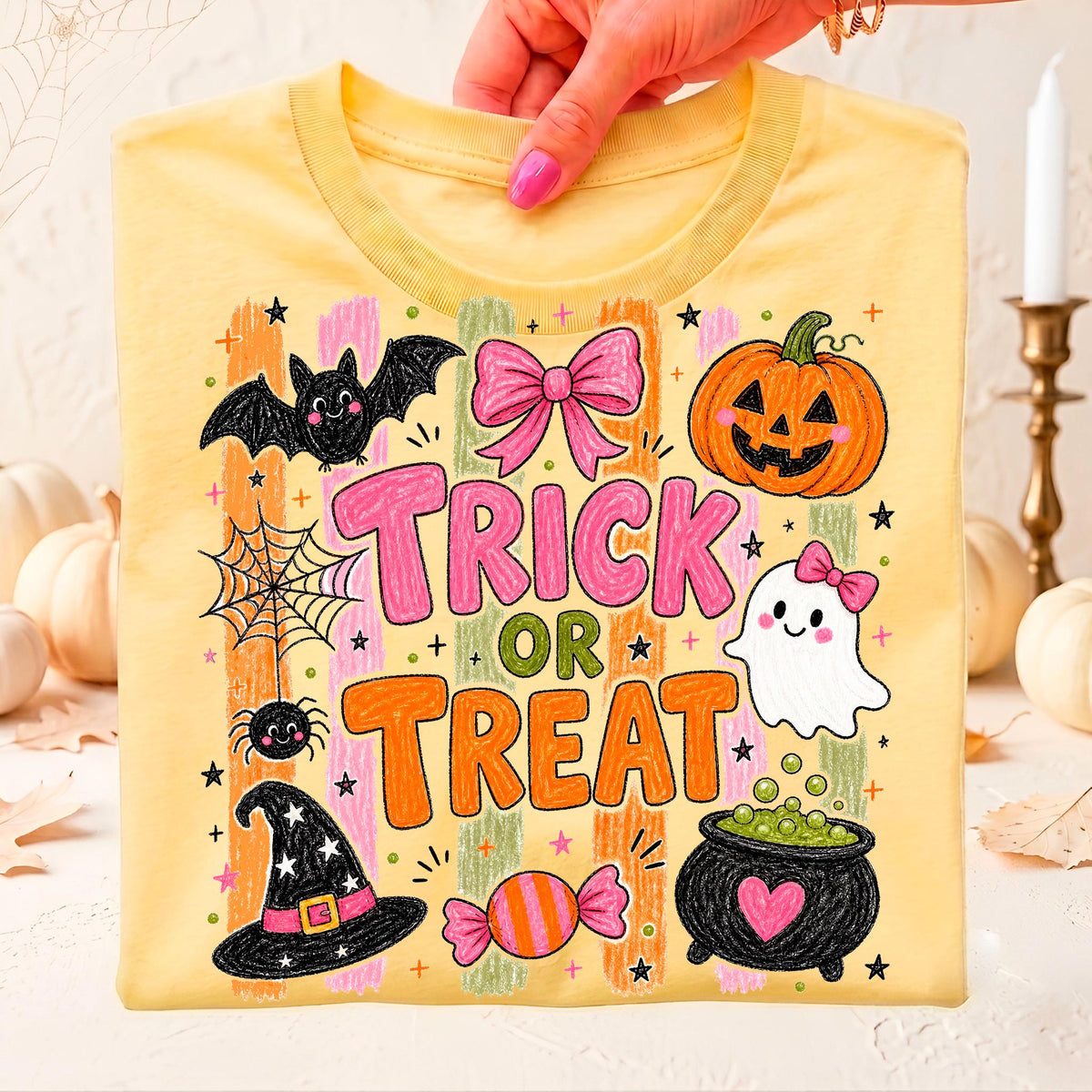 soft yellow halloween tee held up showing a pumpkin ghost and cauldron